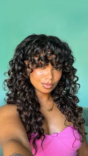 try on a curly hairstyle with bangs, accentuating the curls that beautifully frame the face, ideal for a voluminous look