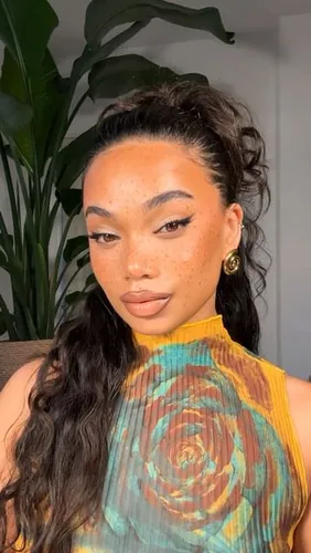 Try on this hairstyle featuring gracefully pinned half-up half-down with curled tendrils accentuating the face, set against an indoor backdrop.