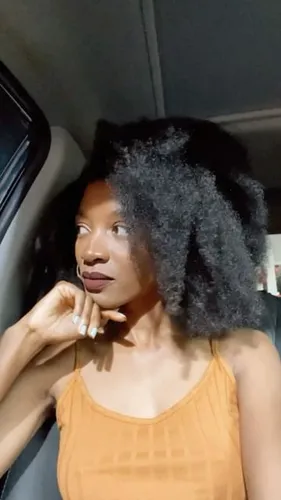 Try on a voluminous afro hairstyle. The person showcases a textured, black afro, expressing elegance and natural beauty.