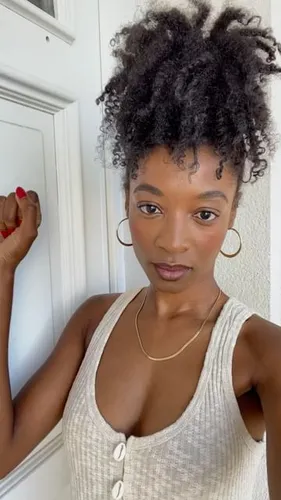 Try on this hairstyle featuring a voluminous curly updo, perfect for textured hair.