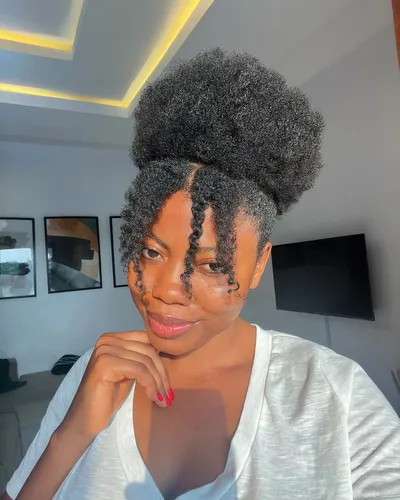 Try on a sophisticated hairstyle featuring a high puff on top with a few curly tendrils elegantly styled on the side.