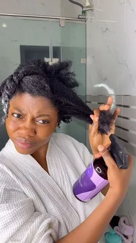 Try on a messy hairstyle as a woman in a white robe holds up strands of her black hair while applying product with a dispenser