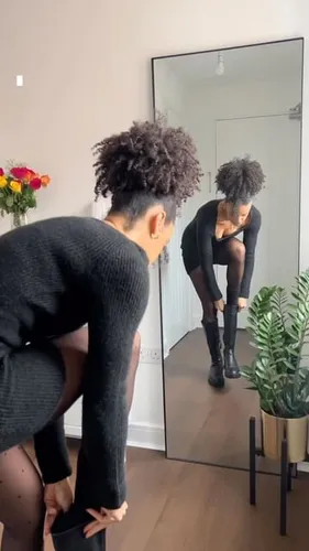 Try on a short, curly hairstyle as shown on a person adjusting their boot in front of a mirror