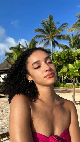 Try on a hairstyle featuring voluminous, shoulder-length curly hair, ideal for a sunny, tropical setting.