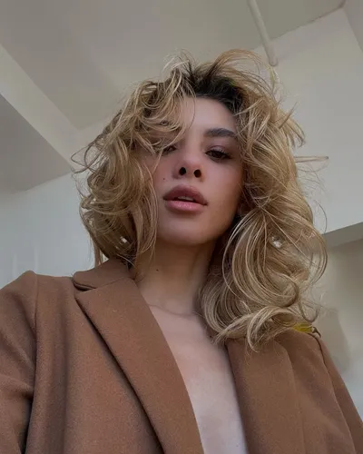 try on a voluminous, curly, blonde hairstyle, showcased in natural, flowing curls with some subtly sunlit highlights.