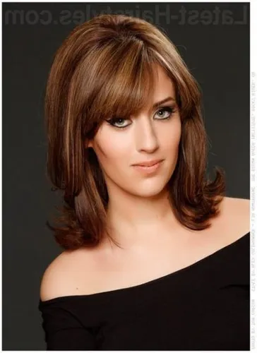 Try on a medium-length layered cut with bangs, styling a natural brown color with subtle highlights. The picture showcases her with a gentle, tapered style that gives a soft framing to the face.