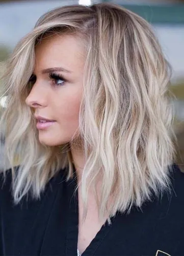 Try on this medium length wavy hairstyle with natural blonde highlights, providing a relaxed and stylish look.