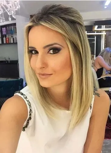 Try on this straight, blonde hairstyle featuring long locks styled with a subtle side part and a smooth finish.