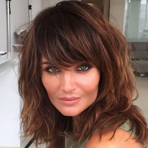 try on a shaggy hairstyle with bangs featuring light layering, looking modern and effortlessly chic.