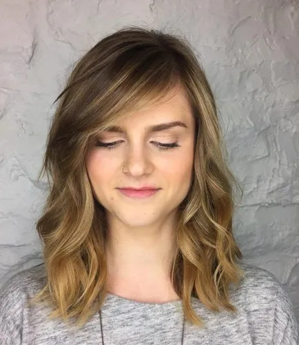 Try on this wavy, shoulder-length hairstyle with subtle highlights and layered cut that frames the face beautifully.