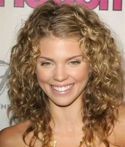 Try out this playful and voluminous medium-length curly blonde hairstyle, which features well-defined spirals and cascades around the face, complementing a cheerful smile.