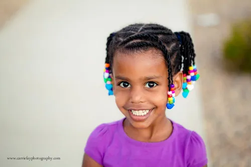 Try on a hairstyle featuring tightly knit braids adorned with colorful beads at the ends