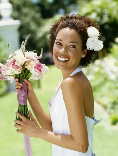 Try on this hairstyle of a woman with short curly hair, embellished with white flowers. The overall style exudes a joyful and festive aura, suitable for special occasions like weddings.