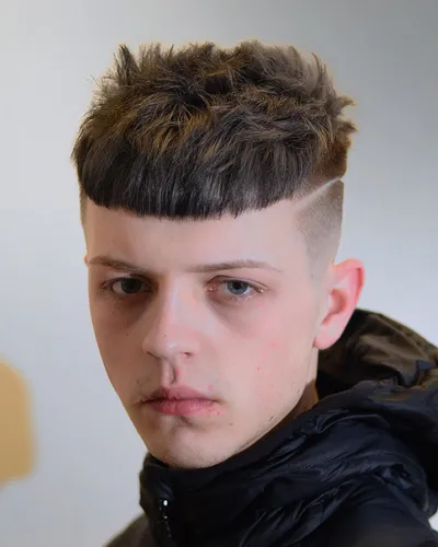Try on a modern bowl cut hairstyle with textured hair on top and neatly shaved sides, as displayed by the person in the image.