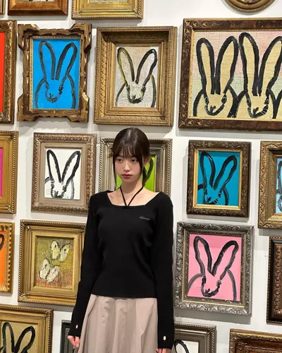 Try on medium-length straight hairstyle seen in this image, fitting for an artistic setting with framed artworks in the background.