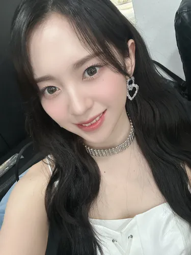 Try on a glamorous style with long, wavy black hair, parted in the middle creating a soft, flattering frame for the face