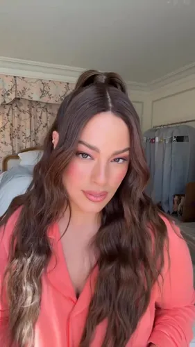 Try on this hairstyle look featuring wavy hair with a half-up, half-down style, complemented by a few loose tendrils framing the face.