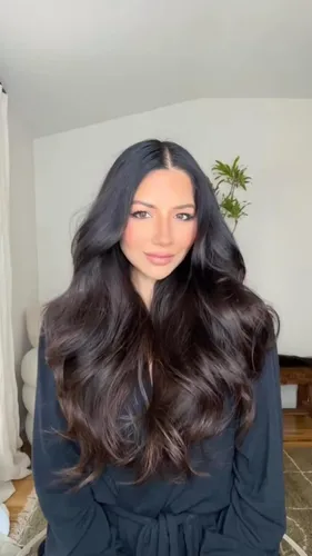 Try on long wavy hairstyle with dark locks that gentle waves framing the face.