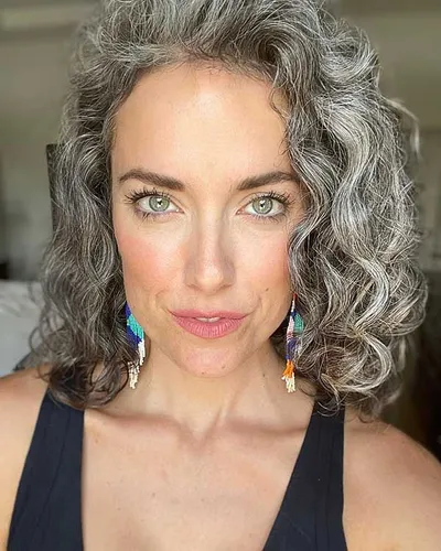 Try on this lush, curly gray hairstyle that frames the face beautifully, enhancing the natural texture and volume.
