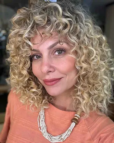 Try on this blonde curly hairstyle, featuring tight, voluminous curls that add a lively and playful look.