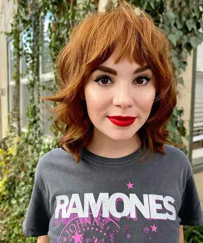 Try on this short wavy hairstyle with bangs, featuring curls that add volume and a lively bounce, perfectly framing the face