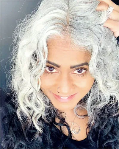 Try on this long curly gray hairstyle that displays voluminous curls and waves flowing freely.