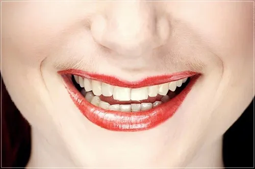 The image focuses on a close-up of a smiling woman's mouth, showcasing vibrant red lips and white teeth. There's no visible hairstyle.