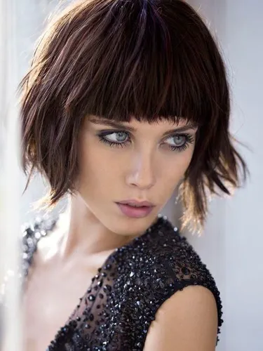Try on a shaggy bob hairstyle, featuring a textured fringe that lightly brushes the eyebrows. This style adds a playful yet chic dimension to the hair.