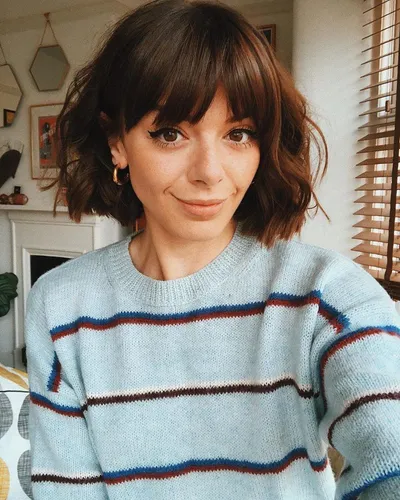 Try on a mid-length bob with bangs. This stylish hairstyle frames the face beautifully, bringing a youthful and chic vibe.