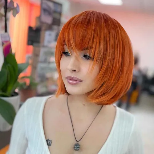 try on a vibrant orange bob haircut with sleek bangs, covering the eyebrows slightly.