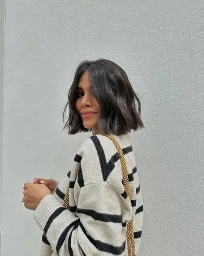 Try on a trendy, shoulder-length bob cut with slight waves, adding a playful and chic touch to the hairstyle.