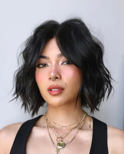 Try on a short, wavy, tousled black hairstyle with choppy layers and a slight parting on the left, adding a trendy, relaxed vibe.