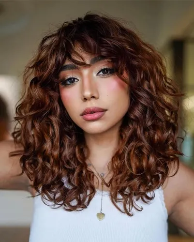 Try on this voluminous curly hairstyle with soft bangs framing the face.