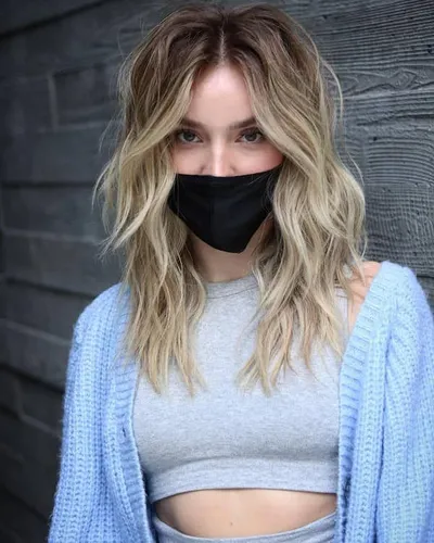 Try on this medium-length, wavy hairstyle with subtle blonde highlights, set against a wooden backdrop